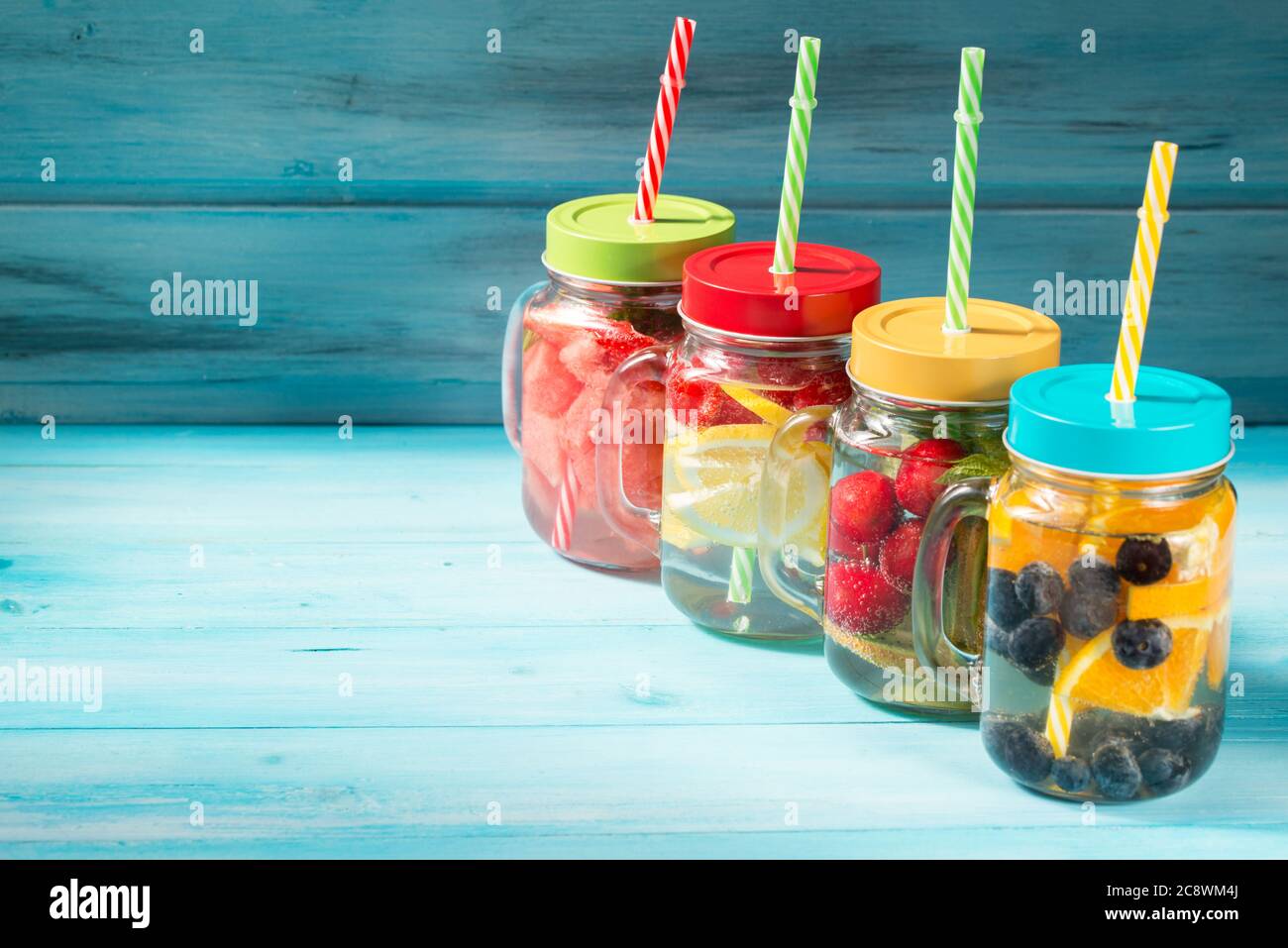 Verschiedene Detox-Wassercocktails in Gläsern auf Holzhintergrund, frische Beeren und Früchte mischen sich Stockfoto
