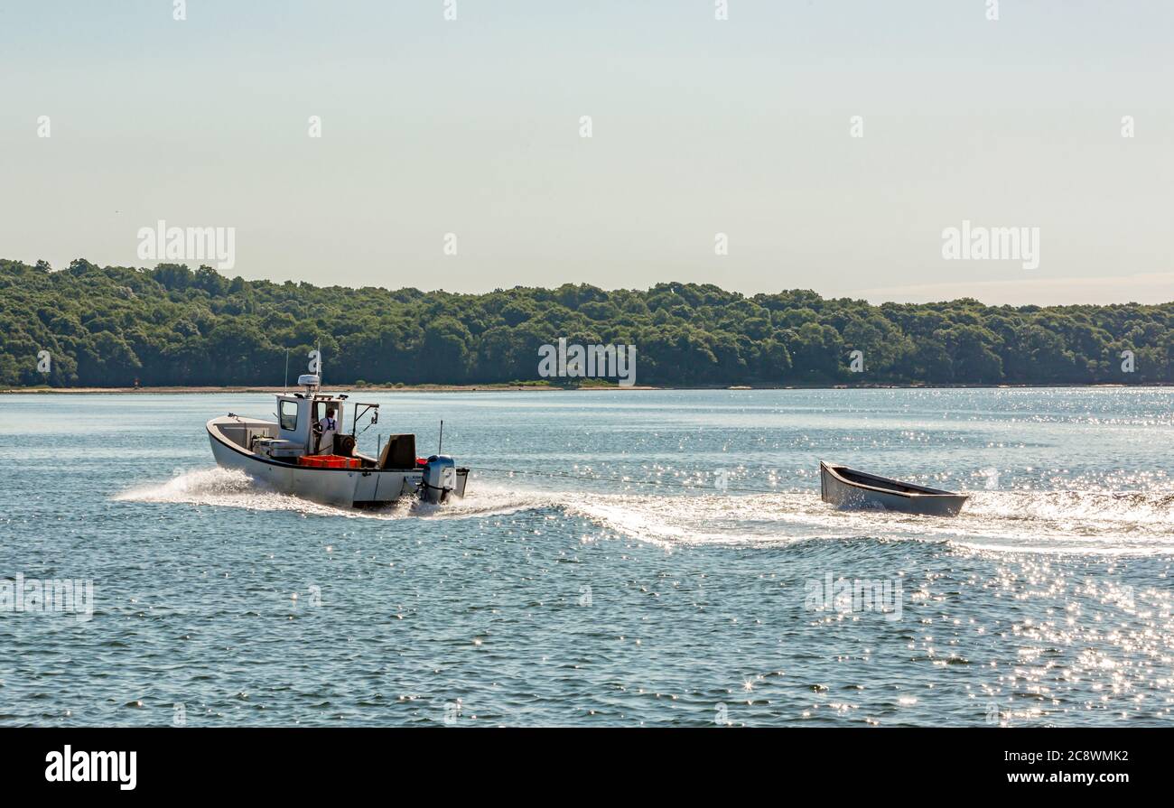 Kleines Fischerboot, das einen kleinen Dingy vor der Küste von Shelter Island, NY zieht Stockfoto