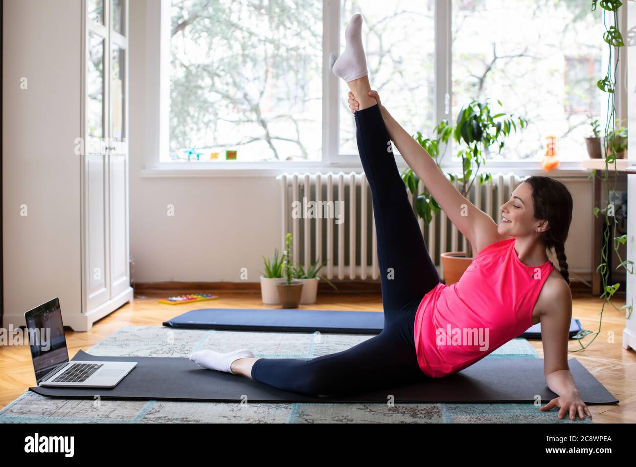 Schöne junge Frau Ausübung Pilates, Yoga, Fitness zu Hause Blick auf den Laptop Stockfoto