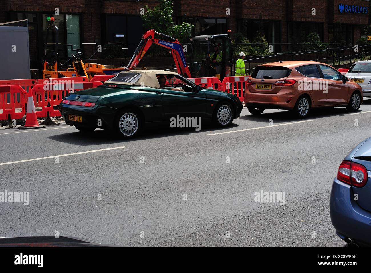 1998 Alfa Romeo im Sommer stecken Straße arbeitet mit Mini Bagger bei der Arbeit Stockfoto