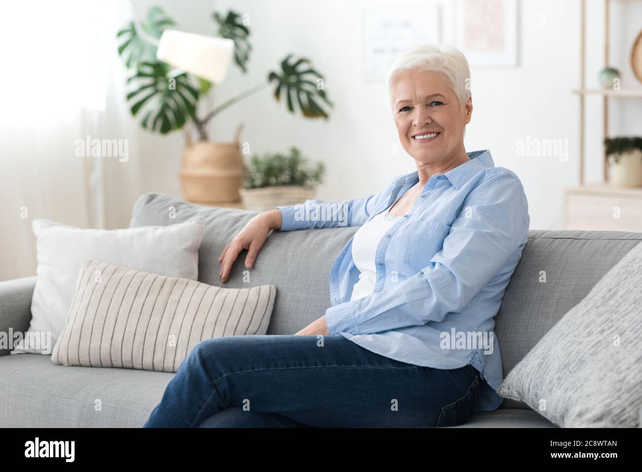Porträt einer älteren Frau, die sich zu Hause auf dem Sofa entspannt und die Ruhezeit genießt Stockfoto