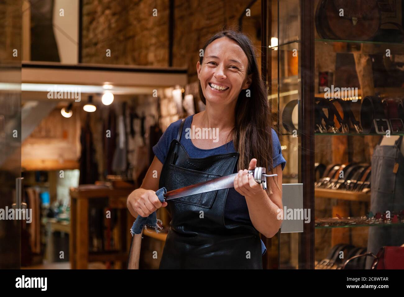 Lederhandfrau vor ihrem Laden mit einem handgefertigten Gürtel. Konzept weibliche Handwerker Lebensstil Stockfoto