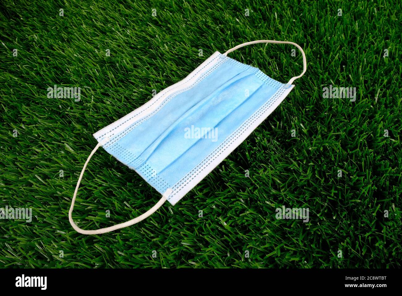 Blaue medizinische Maske auf grünem Gras. Stockfoto