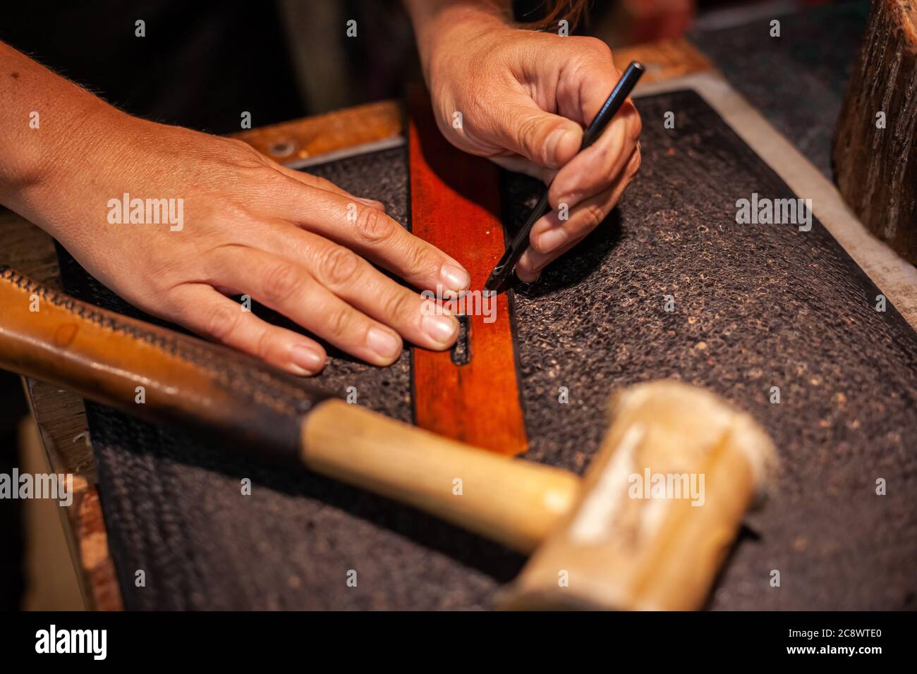 Nahaufnahme der Hände einer Lederhandfrau, die einen handgefertigten Gürtel herstellt Stockfoto