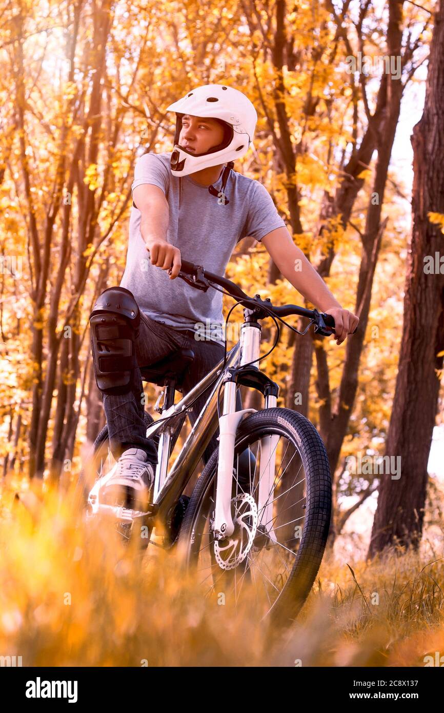 Vertikale Aufnahme eines männlichen professionellen Mountainbikers mit einem Helm im Park Stockfoto