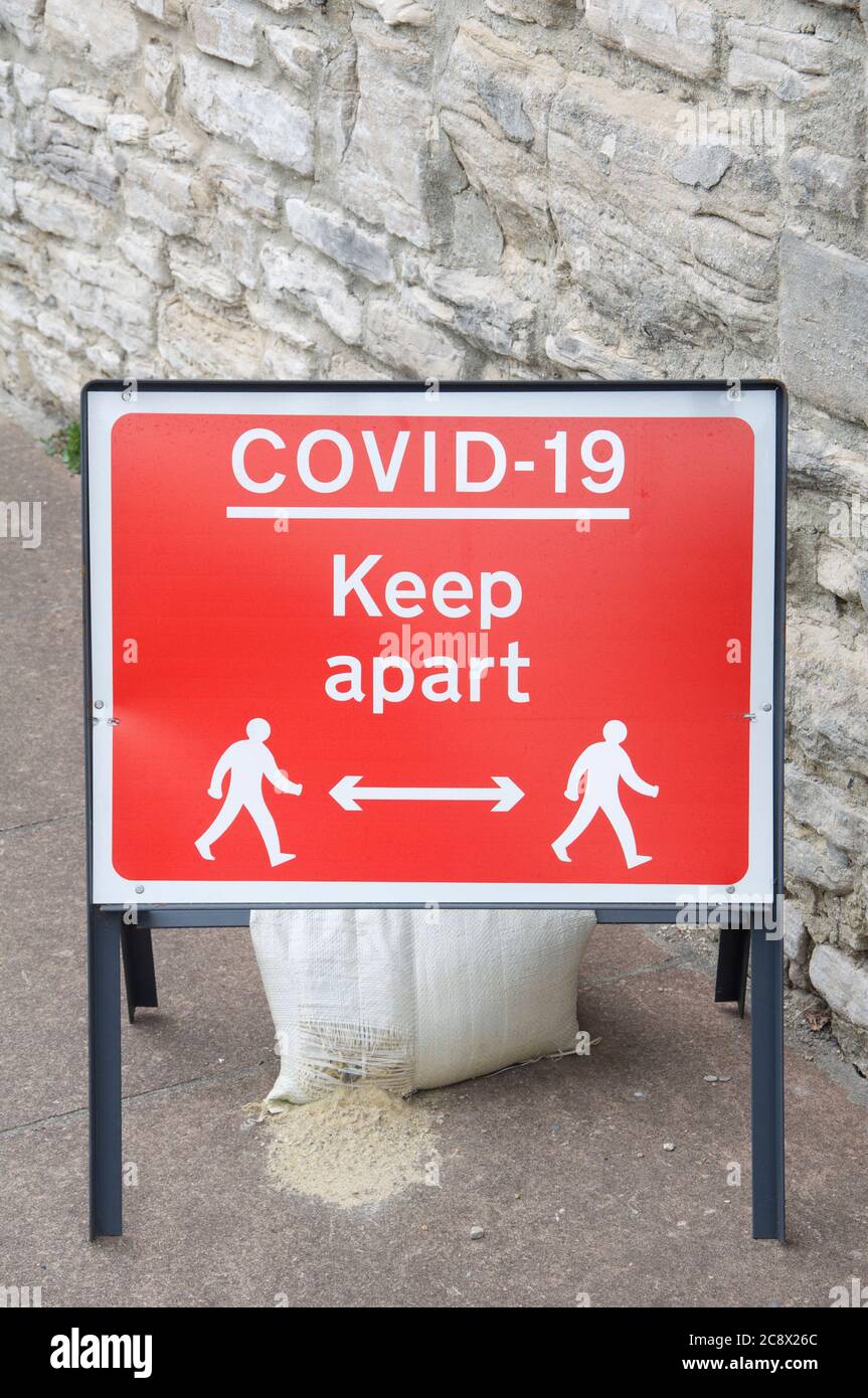 Temporäres rotes Metallzeichen, das soziale Distanzierung berät, liest „Covid-19 halten auseinander“, während der Coronavirus-Pandemie. Dorchester Stadtzentrum, England, Großbritannien. Stockfoto