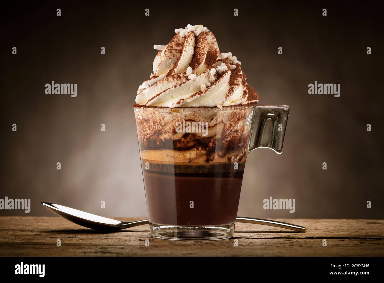 Tasse Kaffee mit Schlagsahne, Milchschaum, Zucker und Kakaopulver. Stockfoto