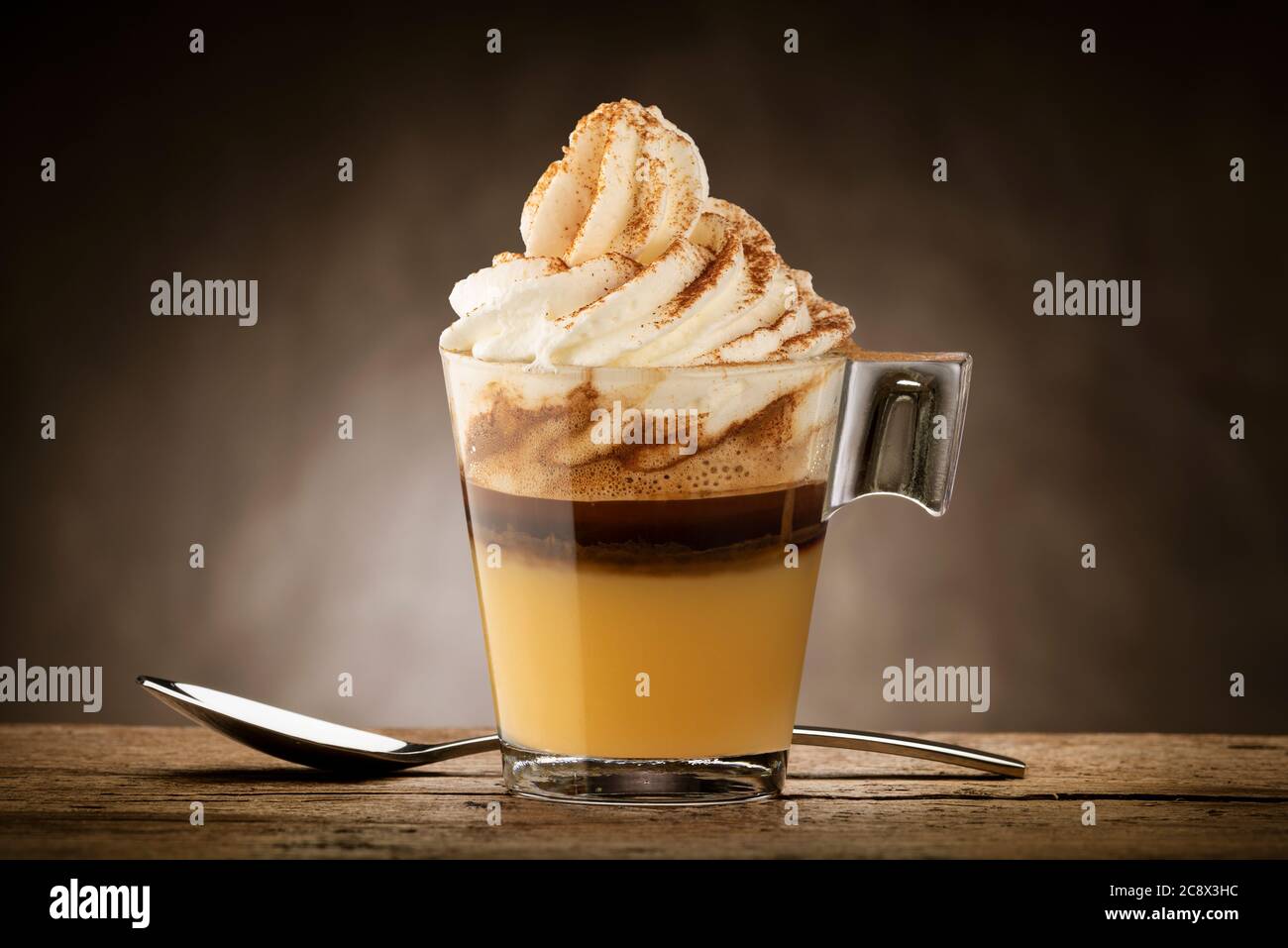 Tasse Kaffee mit Schlagsahne, Karamellcreme und Zimtpulver. Stockfoto