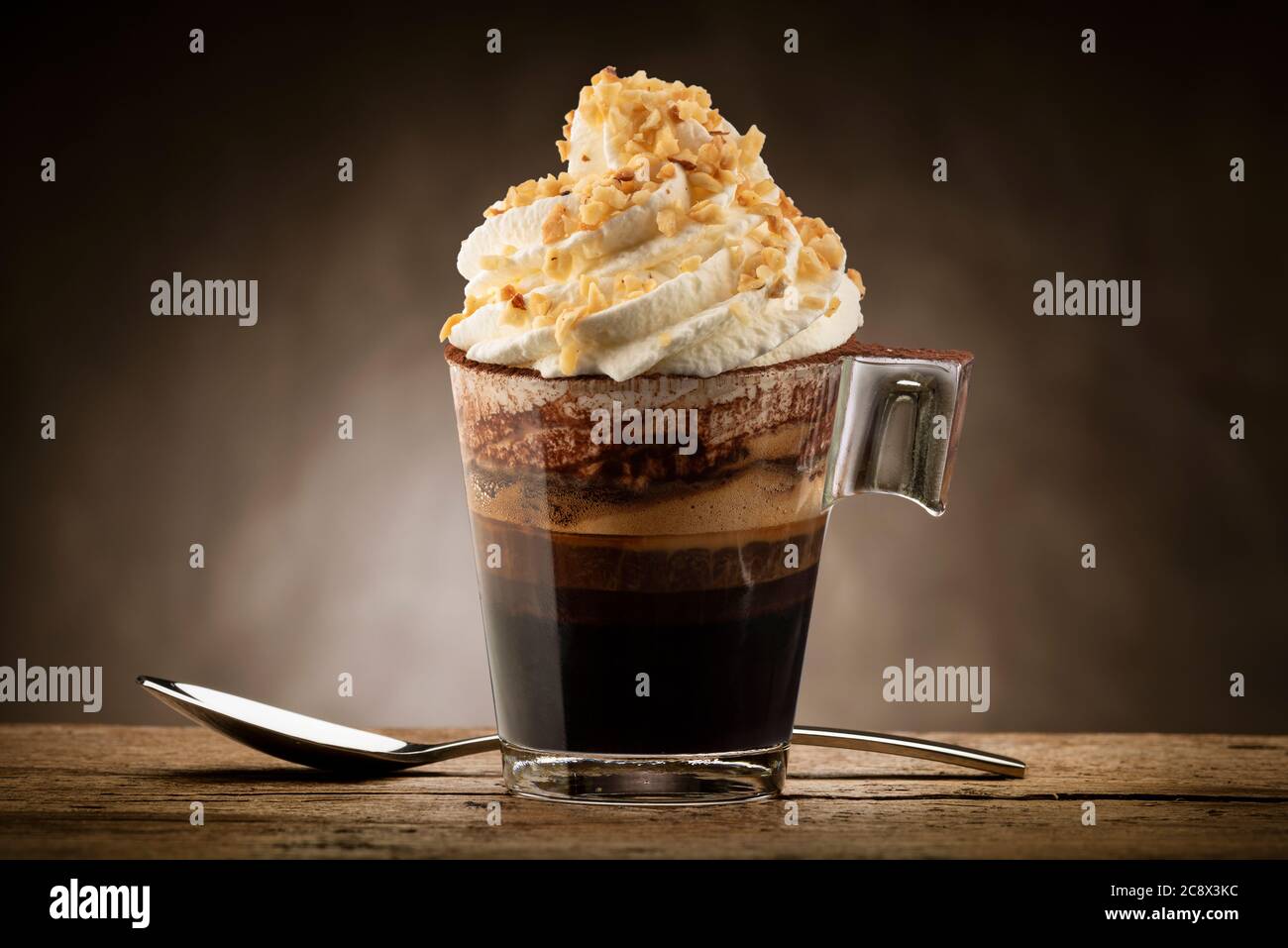 Tasse Kaffee mit Schlagsahne, Schokoladenschaum und Haselnusskorn. Stockfoto