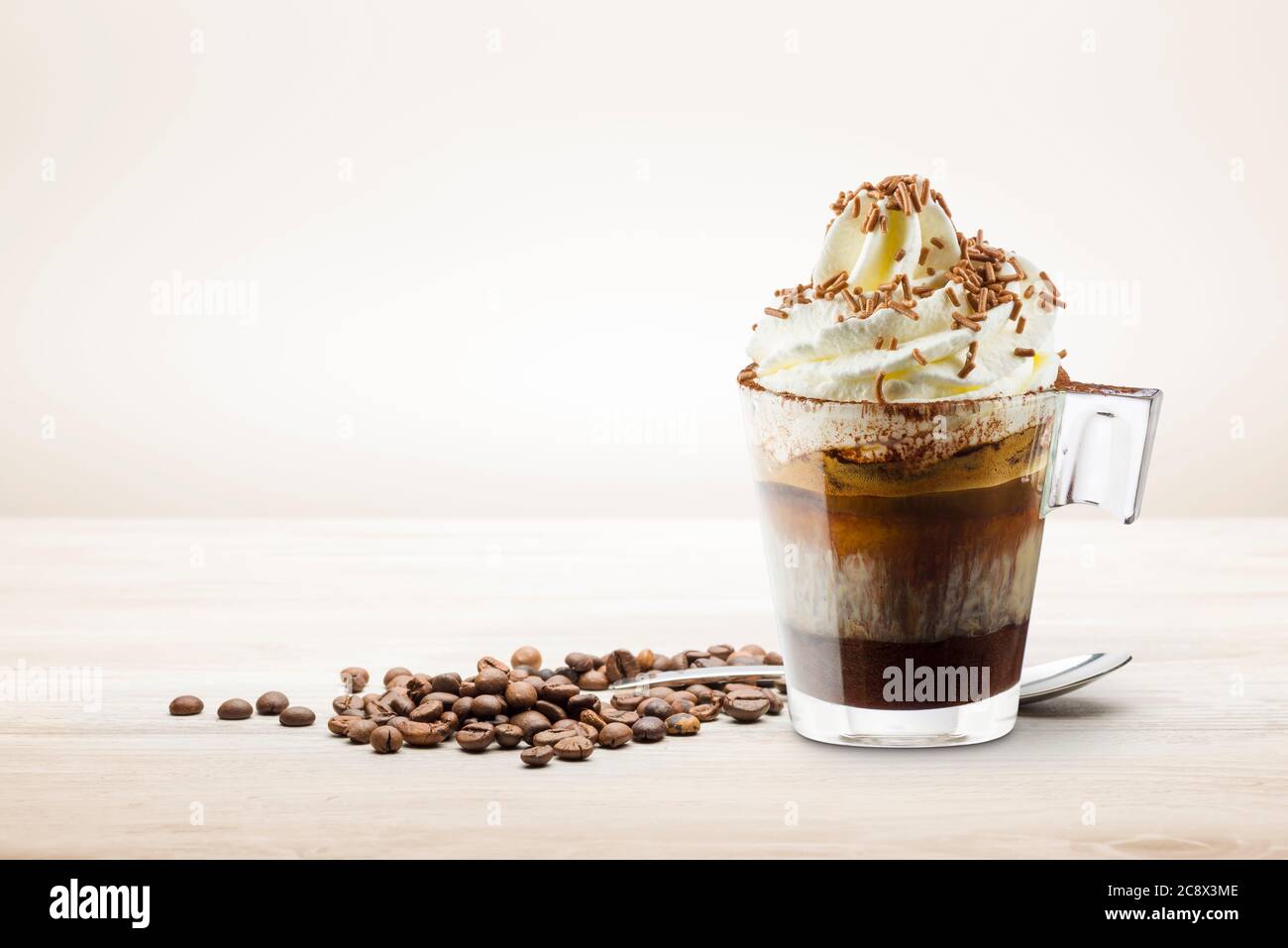 Tasse Kaffee mit Schlagsahne, Milchschaum und Schokoladenstückchen auf Holztisch. Stockfoto
