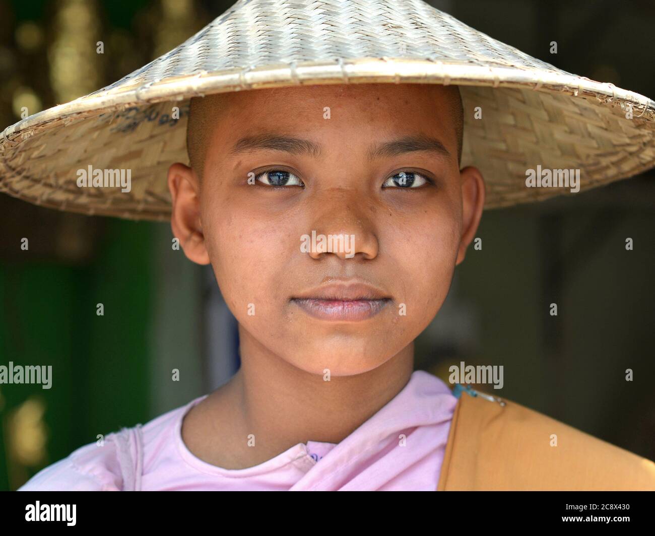 Junge burmesische buddhistische Nonne mit rasierten Kopf trägt einen traditionellen asiatischen konischen Hut. Stockfoto