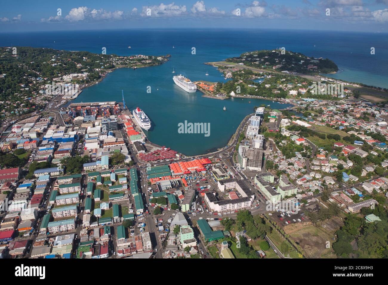 Castries, Hafen und Hauptstadt von St. Lucia in der Karibik, Westindien. Luftaufnahme von Straßen, Gebäuden und zwei Kreuzfahrtschiffen mit Flughafen oben rechts Stockfoto