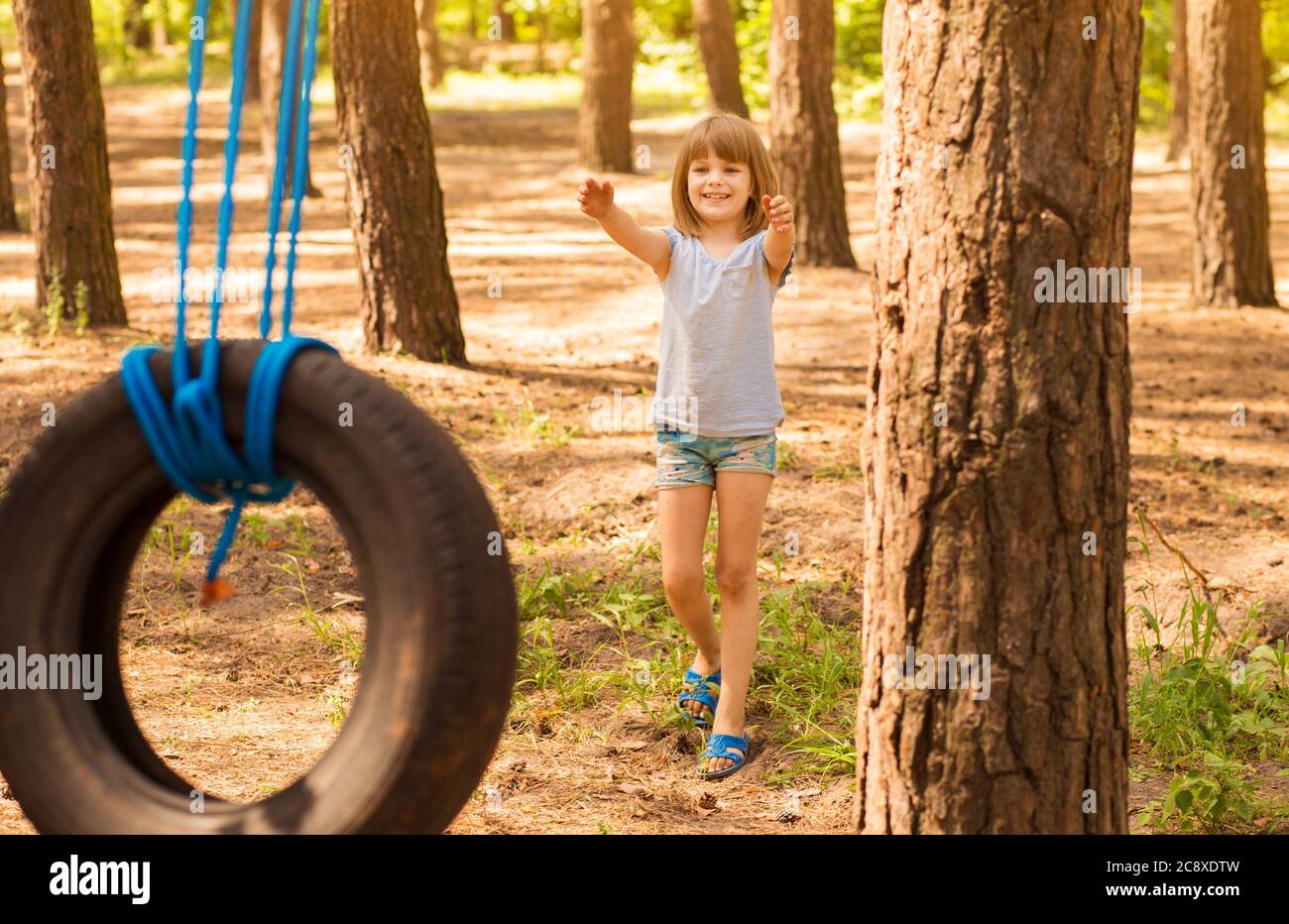 Glücklich aktives Kind Mädchen spielen auf Schaukel Rad im Wald an sonnigen Sommertag. Sommer Aktivitäten im Freien für Kinder. Vorschulkind mit Spaß und Swingi Stockfoto