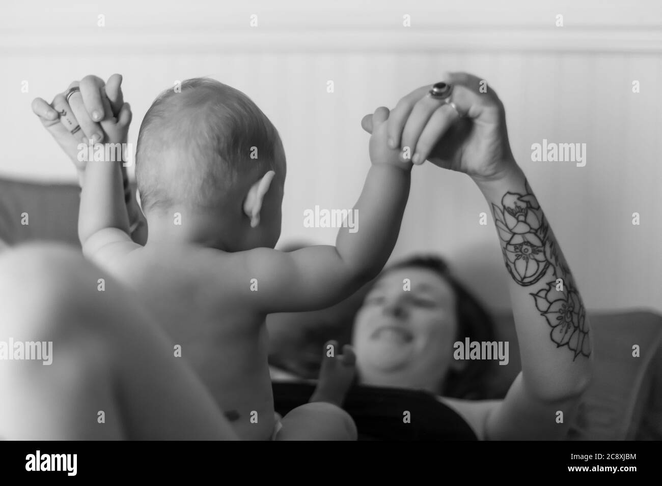 Mutter Und Baby Sohn Freudige Intimitat Ruckansicht Eines Babys Das Auf Dem Bauch Seiner Mutter Sitzt Wahrend Sie Ihn An Den Armen Halt Schwarz Weiss Portrat Stockfotografie Alamy