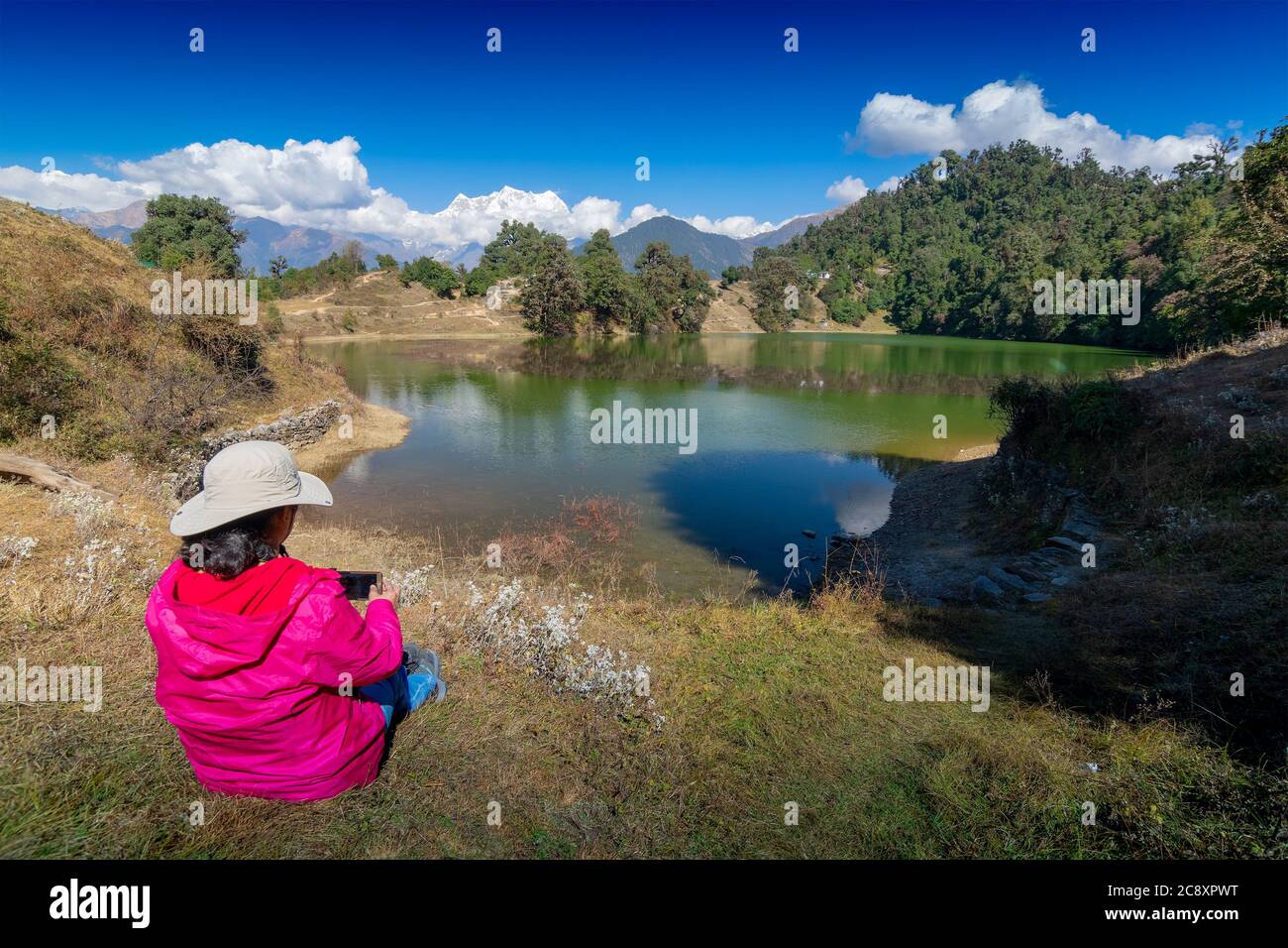 Alleinreisende, alleinreisende Frau, die Deoria Tal mit ihrem Handy fotografiert, Hochgebirgssee in Uttarakhand, Indien. Blauer Himmel mit Schnee Stockfoto