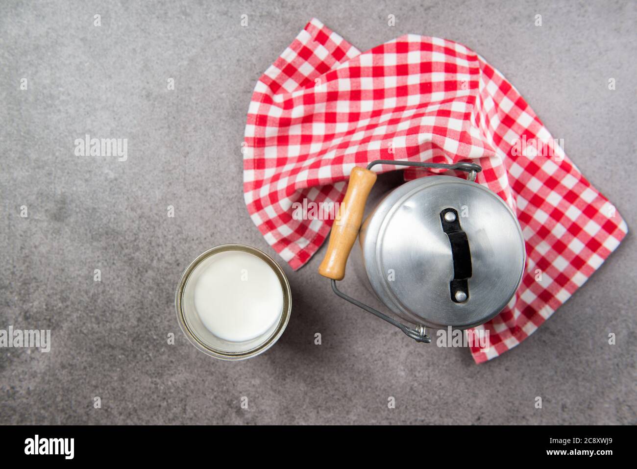 Milchaluminiumkannne und Glas Milch auf einem Steintisch, Draufsicht Stockfoto