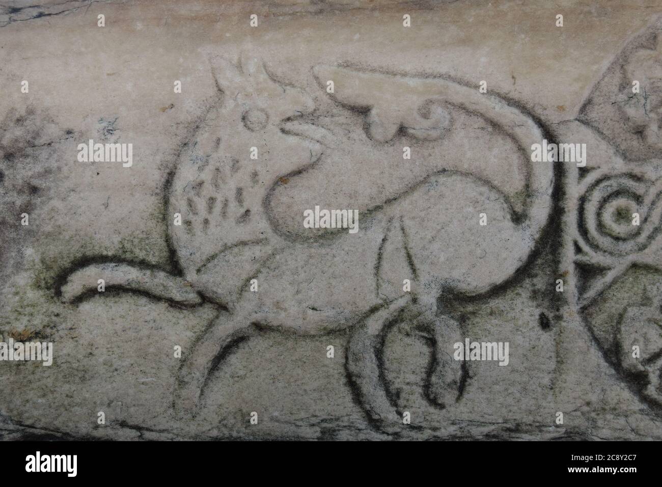 Steinschnitzerei des Schweifes jagenden Hundes oder mythologische Kreatur auf alten Agora Marmorsäule. Stockfoto