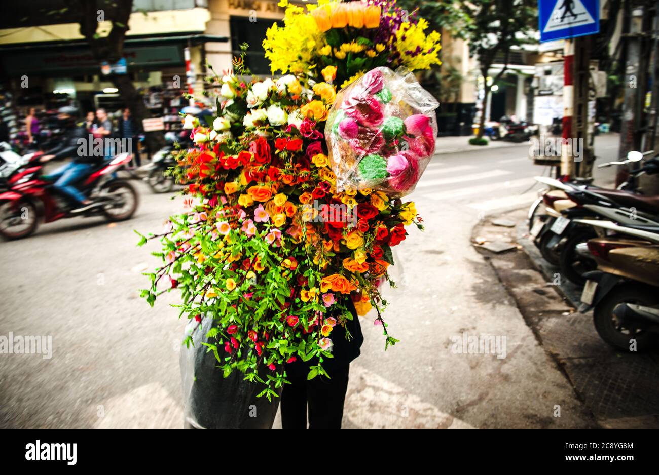 Frau trägt Blumen durch die Straßen von Ho Chi Min City, Vietnam, Südostasien Stockfoto