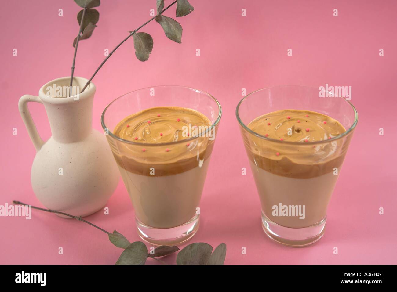 Zwei Gläser hausgemachten Eiskaffees mit dekorativer weißer Vase. Rosa Hintergrund Stockfoto