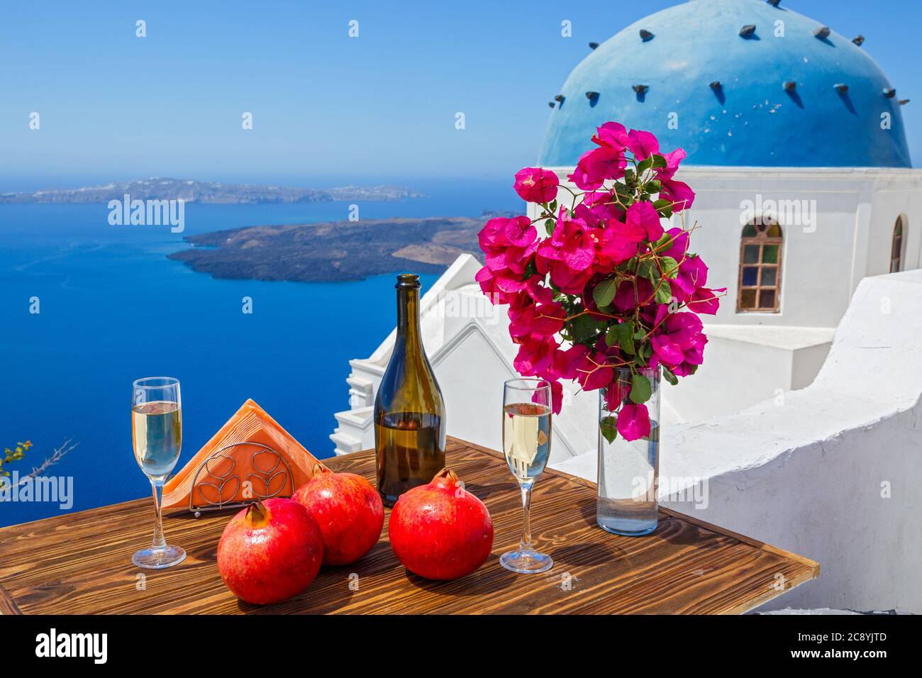 Wein und Granatapfel für zwei Personen auf dem Hintergrund des Meeres und der Insel Santorini. Stockfoto