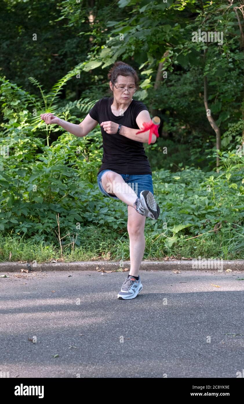 Eine Frau spielt Jianzi, eine traditionelle chinesische Sportart, bei der die Spieler versuchen, einen schwer gewichteten Federball in der Luft zu halten, indem sie ihren Körper benutzen. Stockfoto