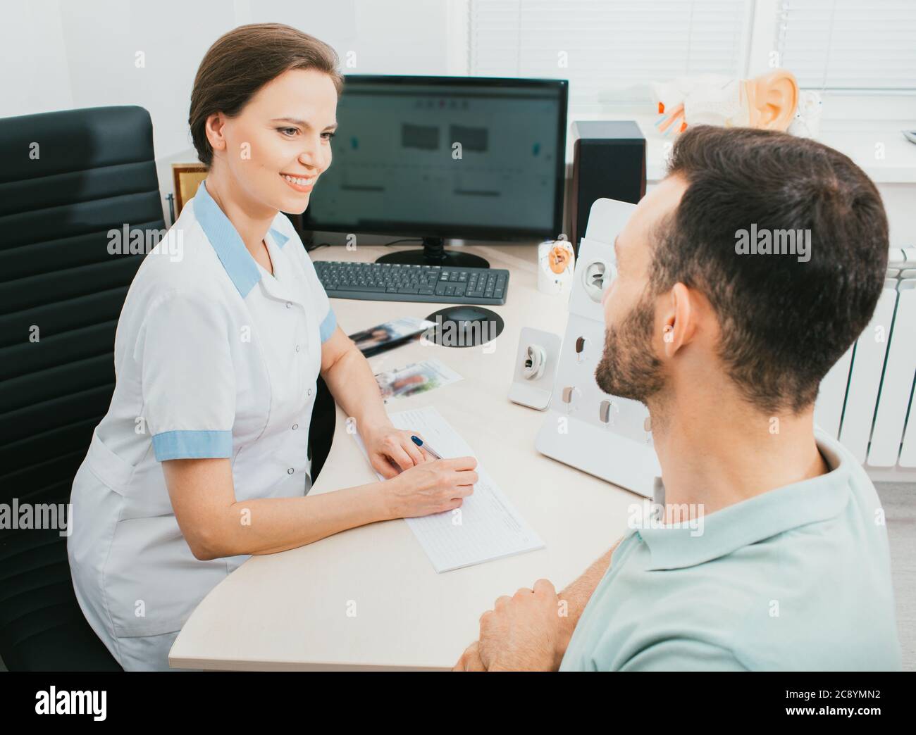 HNO-Arzt hilft einem erwachsenen Patienten bei der Wahl eines Hörgeräts. Hörbehandlung mit einem Hörgerät Stockfoto