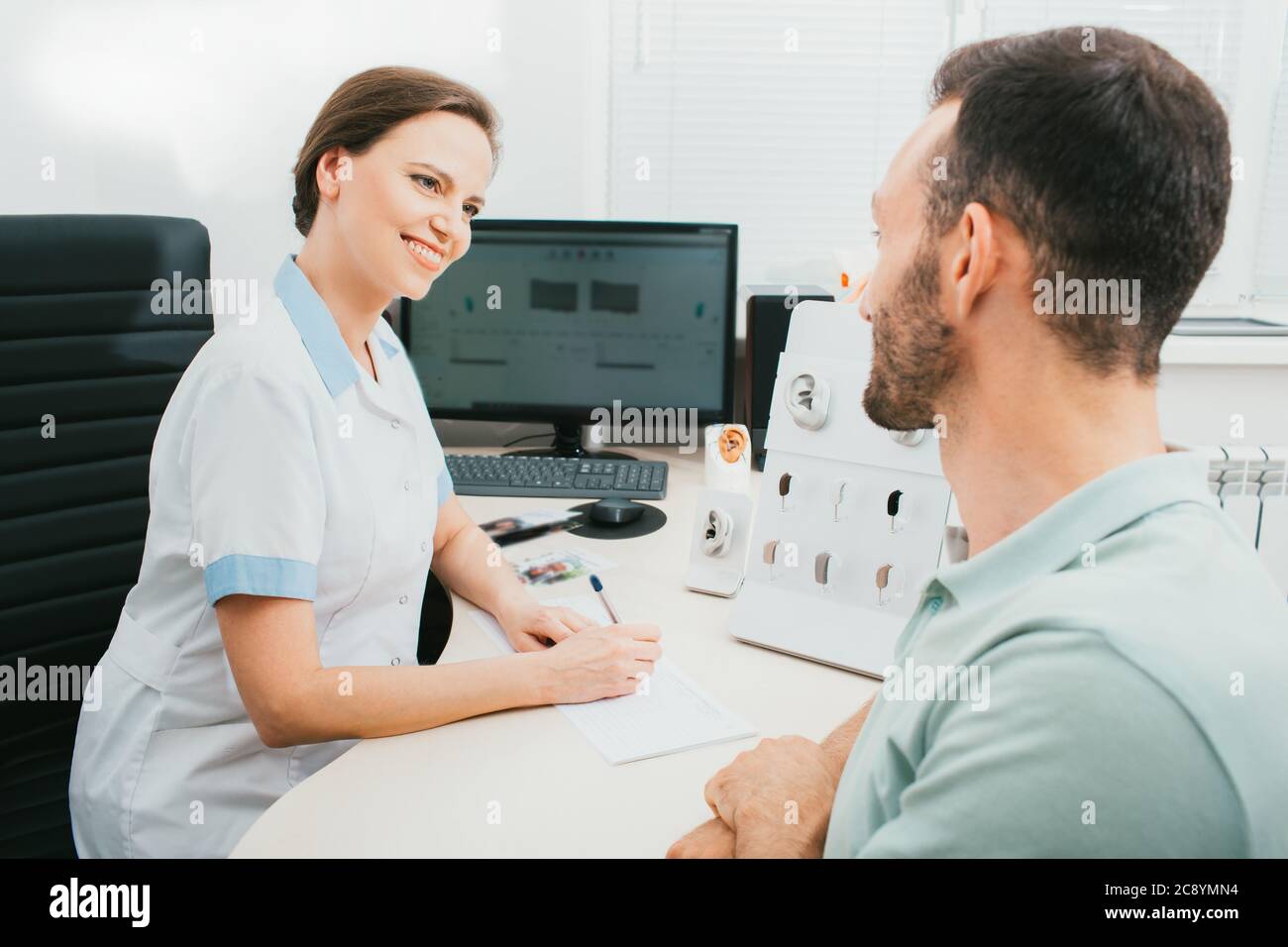 Konsultation, ein Audiologe kommuniziert mit einem erwachsenen Mann in einer Hörklinik. Arzt und Patient, Diagnose und Behandlung des Gehörs. Stockfoto