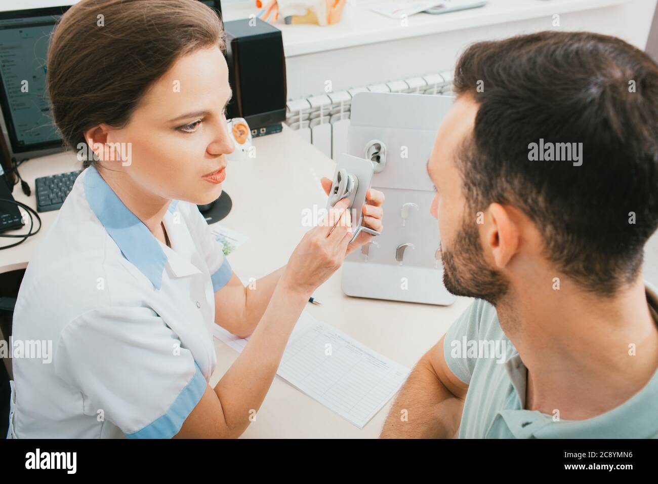 Der Arzt eines Audiologen informiert den Patienten über das Hörgerät. Auswahl an Hörlösungen, Hörbehandlung, in-Ear-Hörgeräten Stockfoto