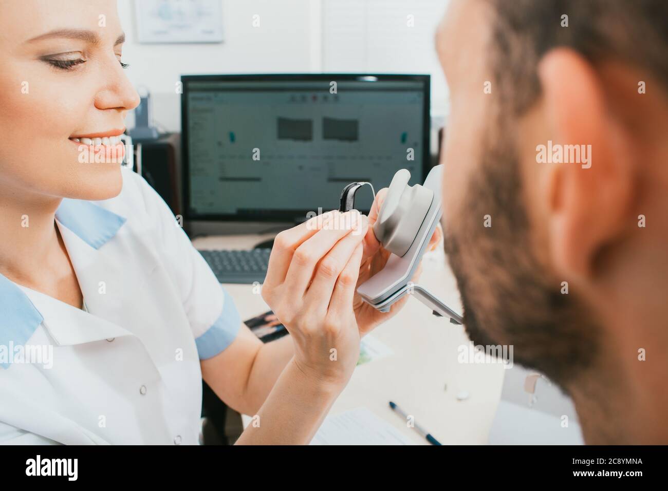 Der Arzt eines Audiologen informiert den Patienten über das Hörgerät. Auswahl an Hörlösungen, Hörbehandlung, in-Ear-Hörgeräten Stockfoto