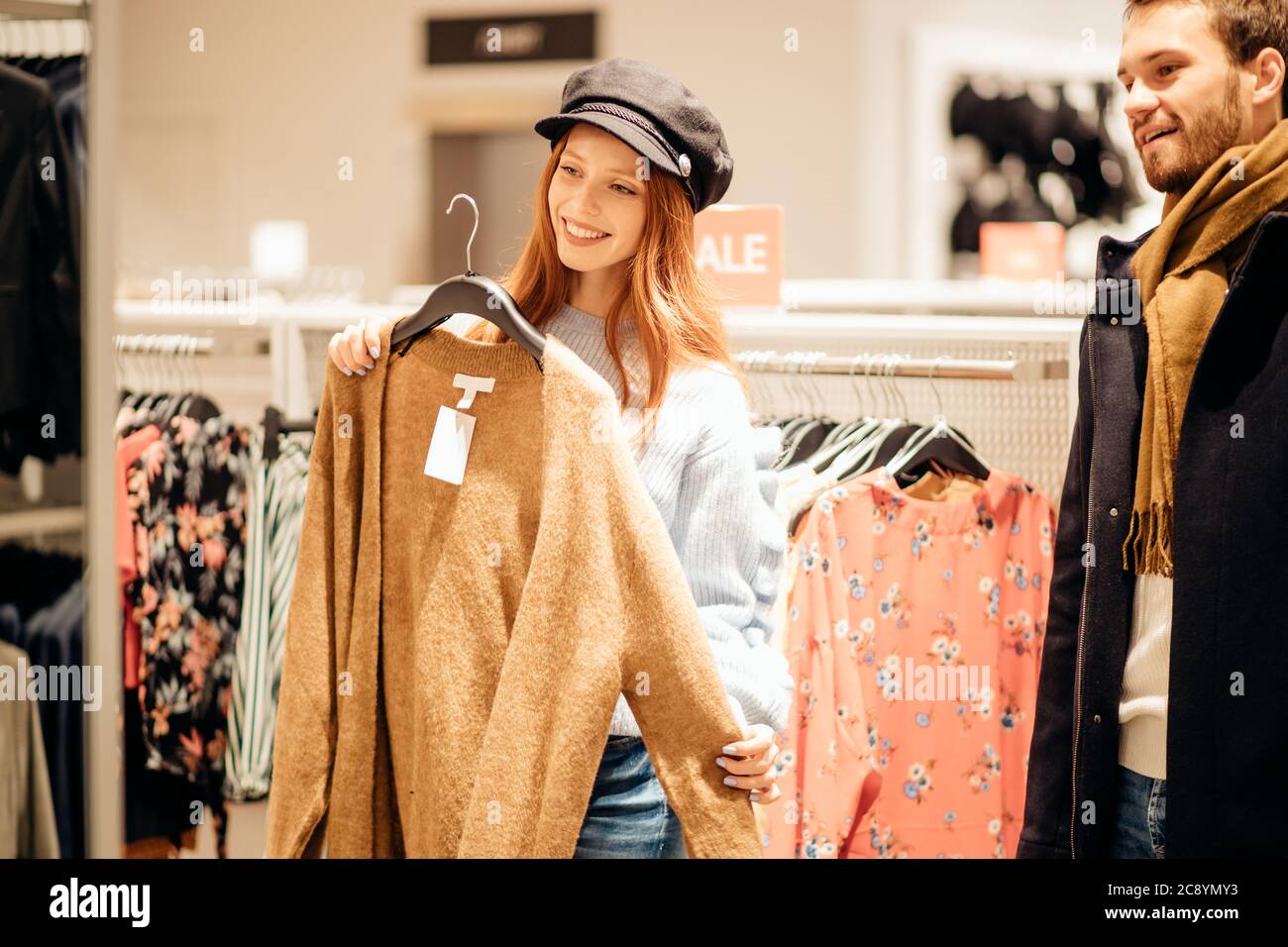 Junge kaukasische Paar zusammen wollen neue Bluse für Frau kaufen, Kleidung im Hintergrund zu speichern Stockfoto