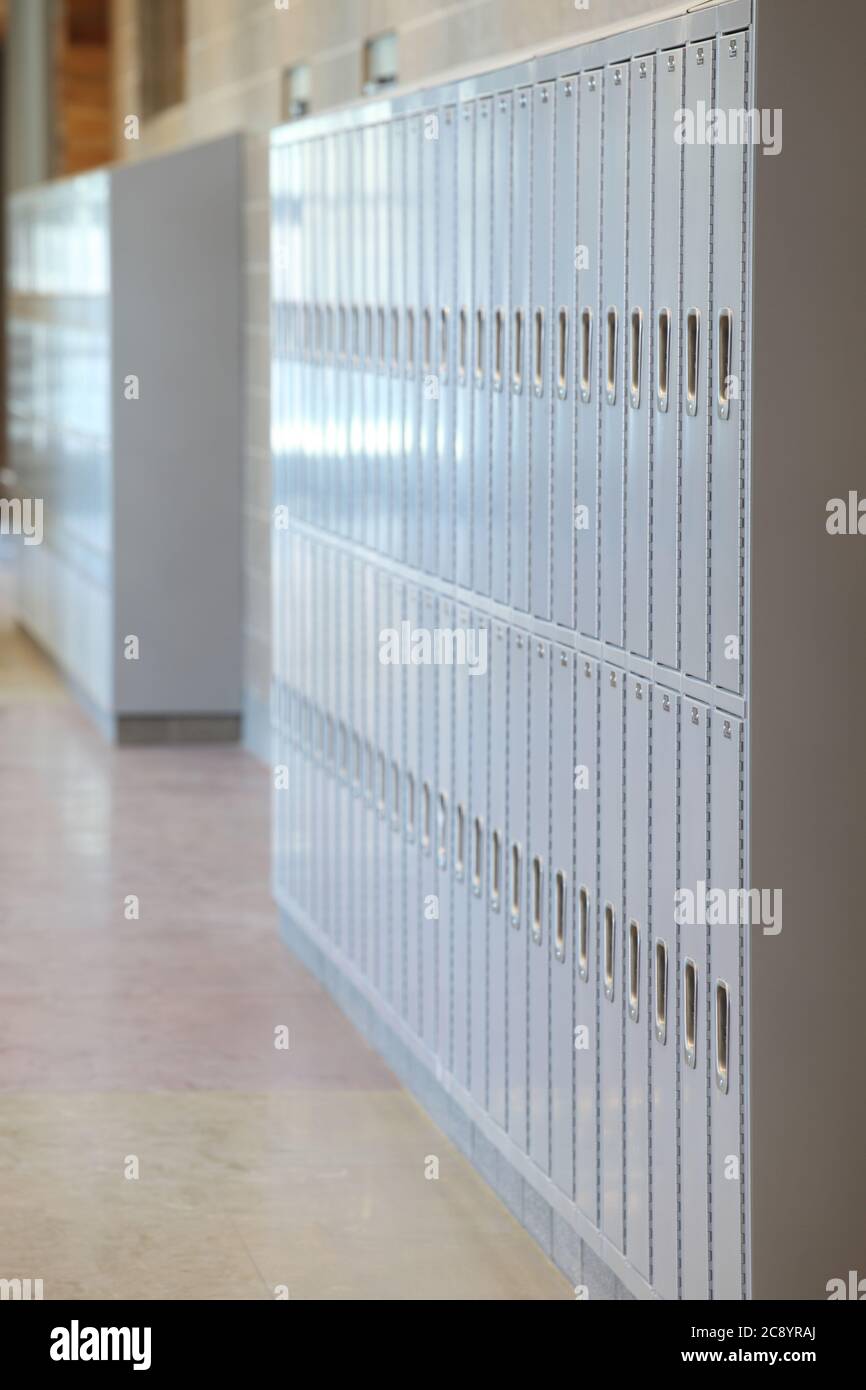 Schließfächer mit Kombinationsschlössern, Seite an Seite im Flur einer High School, mit Fokus zurückgeht in den Hintergrund. Stockfoto