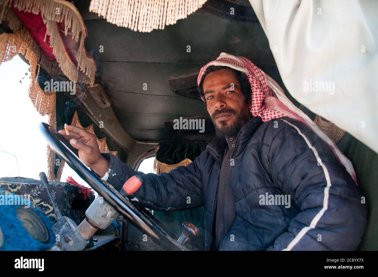 Ein junger Beduinenmensch und Lastwagenfahrer, der in seinem Lastwagen in der Nähe der Stadt Azraq in der Region Badia in der östlichen Wüste Jordaniens sitzt. Stockfoto