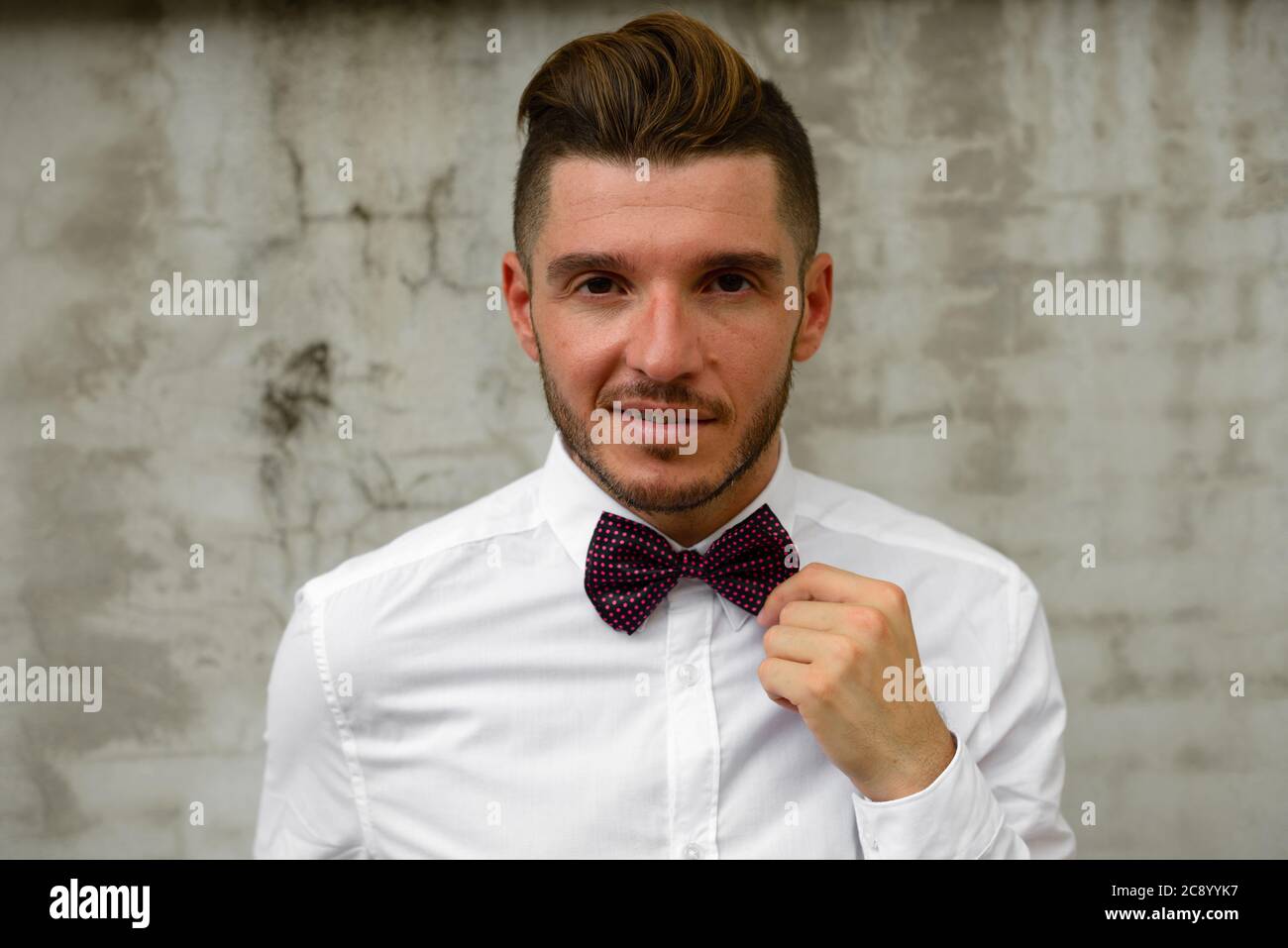 Schöner bärtiger hispanischer Geschäftsmann trägt Fliege im Freien Stockfoto