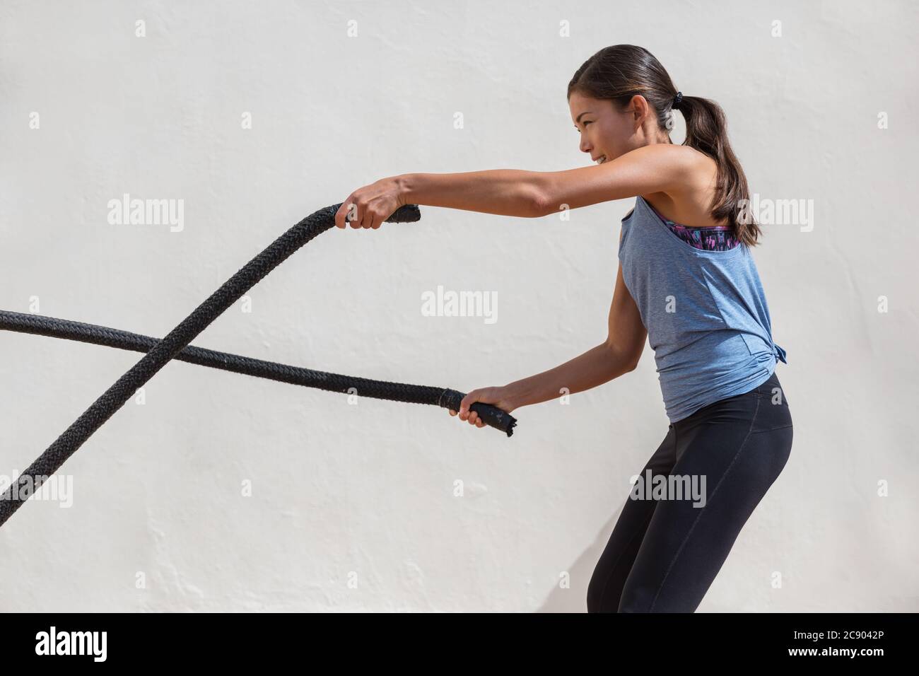 Fitness Frau Training Kampf Seile Training im Fitnessstudio. Mädchen trainieren Arme und Cardio mit Kampfseil für Cross-Fit-Übungen Stockfoto