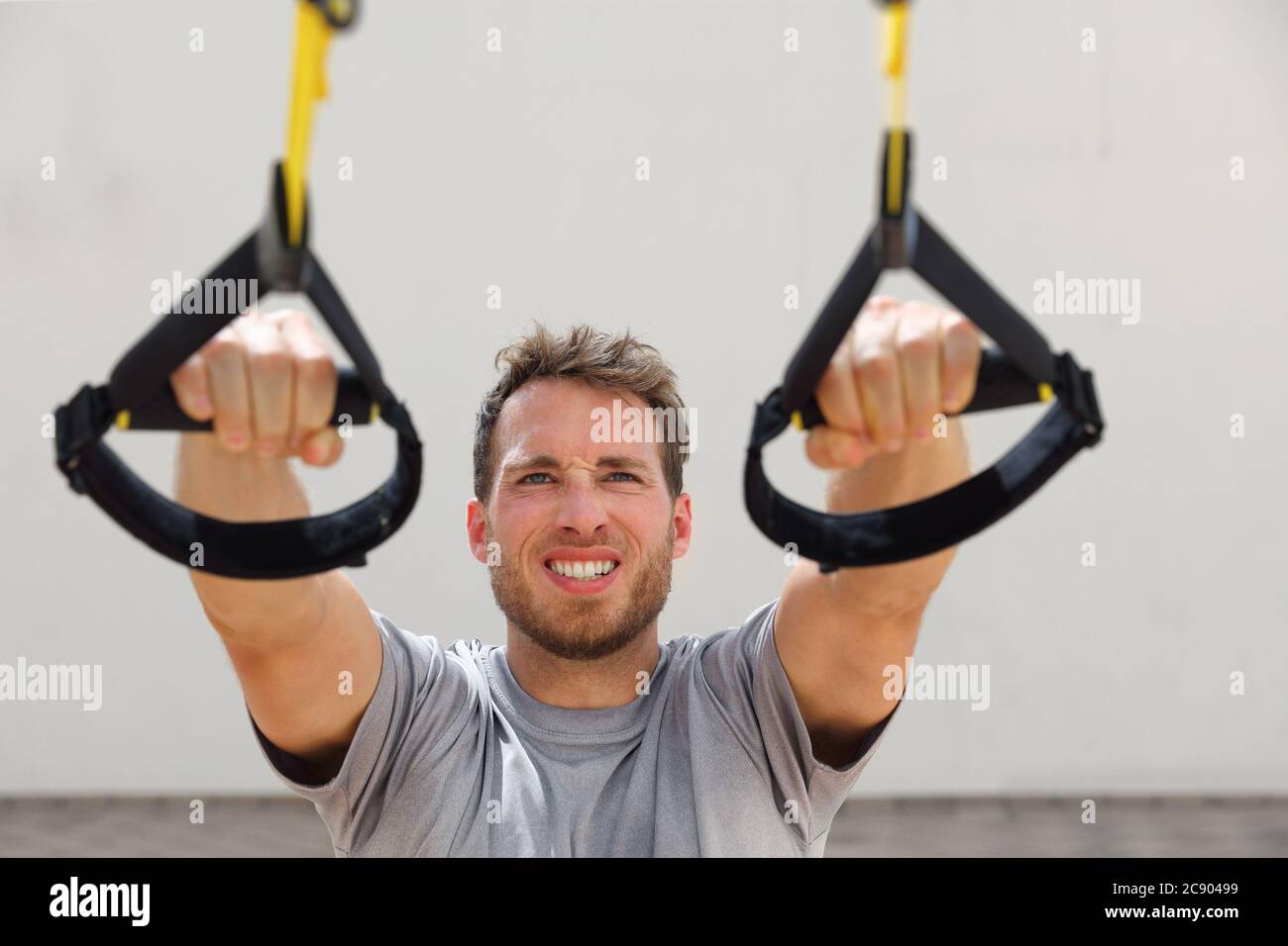 Suspension Straps Übungen Mann Training Arme Workout im Outdoor-Fitness-Studio. Athlet hält hängende trx Griffe tun schräg Pull-ups für Rückenmuskulatur Stockfoto