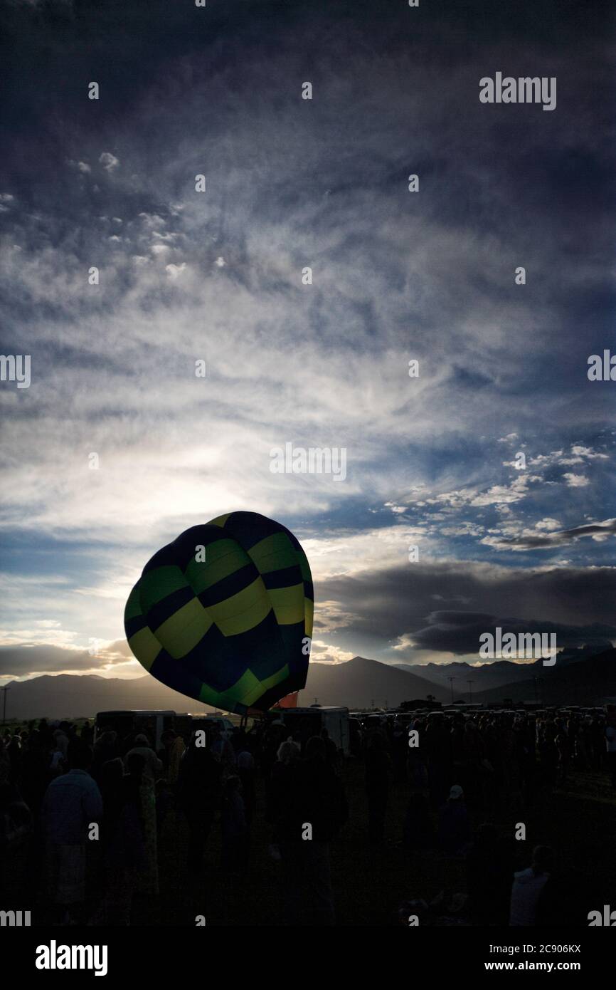 Ein Blick auf einen Heißluftballon, der aufgeblasen wird, und die Sonne beginnt über den Bergen aufzugehen. Stockfoto