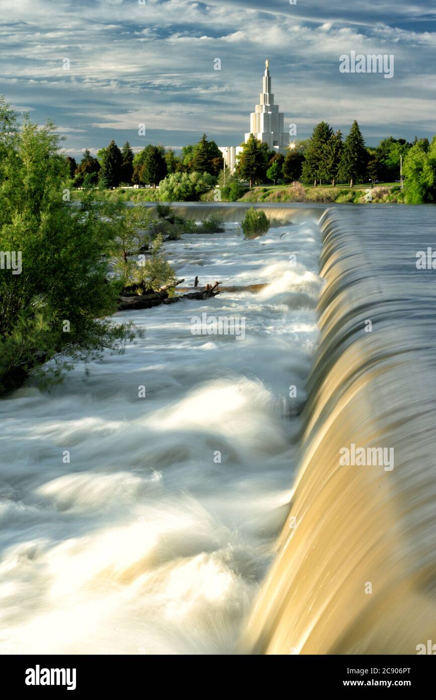 Eine Hochwasserfrühlingsansicht des Wasserfalls, nach dem die Stadt Idaho Falls, ID USA benannt ist. Der Idaho Falls LDS Tempel im Art Deco Stil ist in Stockfoto