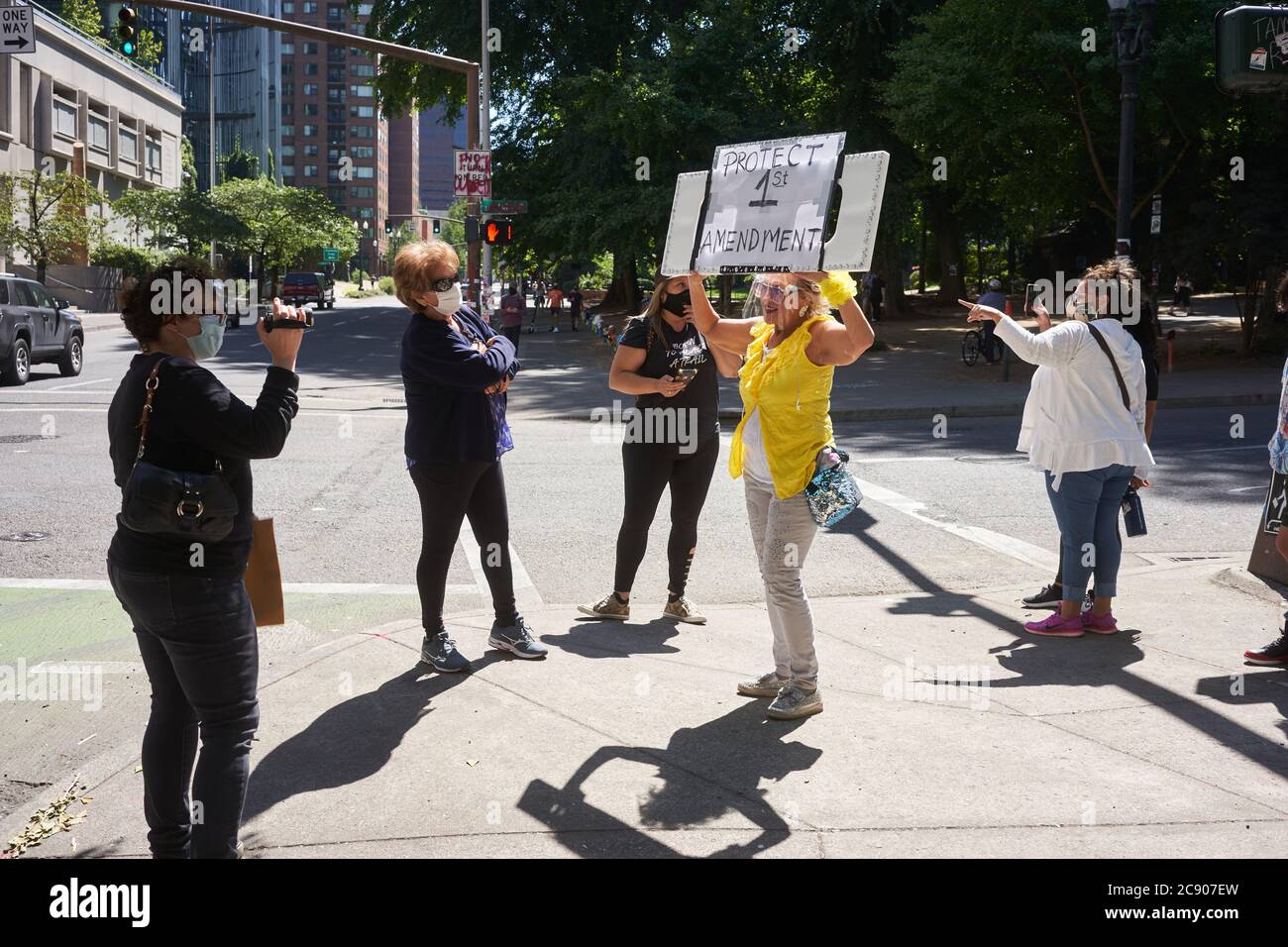 Eine Mutter Protesterin in gelben Posen für einen Videofilmer vor dem Bundesgericht Gebäude in der Innenstadt von Portland, Oregon, am Samstag, 25. Juli 2020. Stockfoto