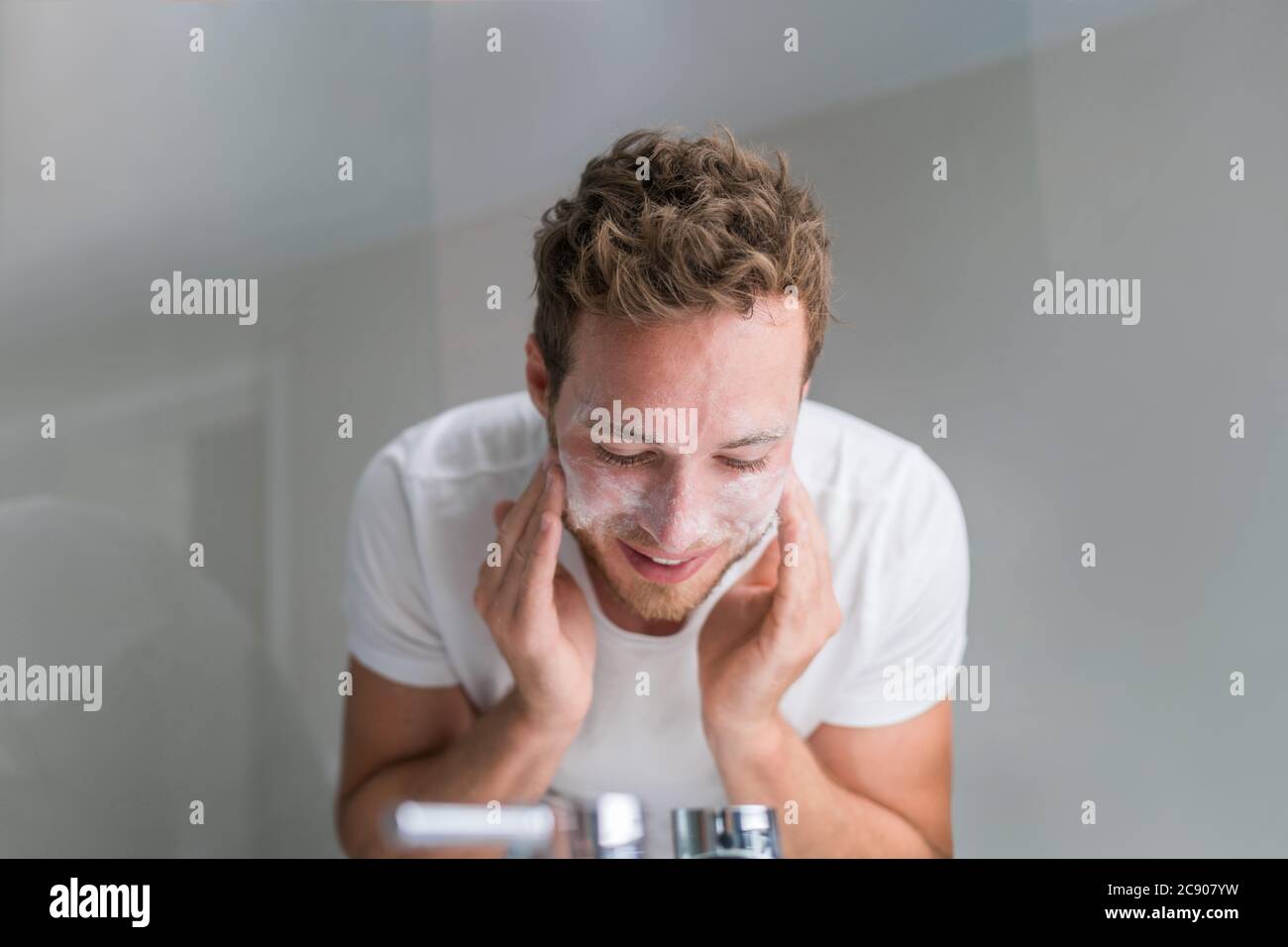 Mann Wasch Gesicht mit Gesichtsreiniger Gesicht Wasch Seife in Waschbecken im Badezimmer zu Hause Stockfoto