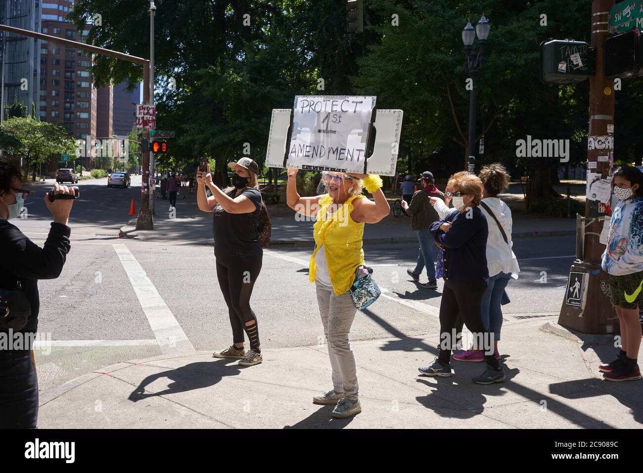 Eine Mutter Protesterin in gelben Posen für einen Videofilmer vor dem Bundesgericht Gebäude in der Innenstadt von Portland, Oregon, am Samstag, 25. Juli 2020. Stockfoto
