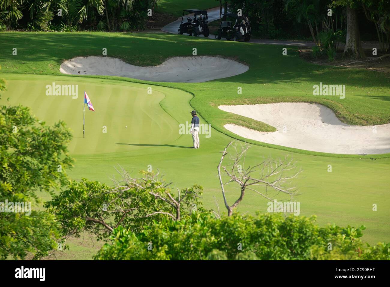 Ein Kaukasischer Mann auf dem Golfplatz ist bereit für den letzten Schlag, eine gute Zeit, startet mit den Golfwagen in Playa del Carmen, Mexiko. Stockfoto