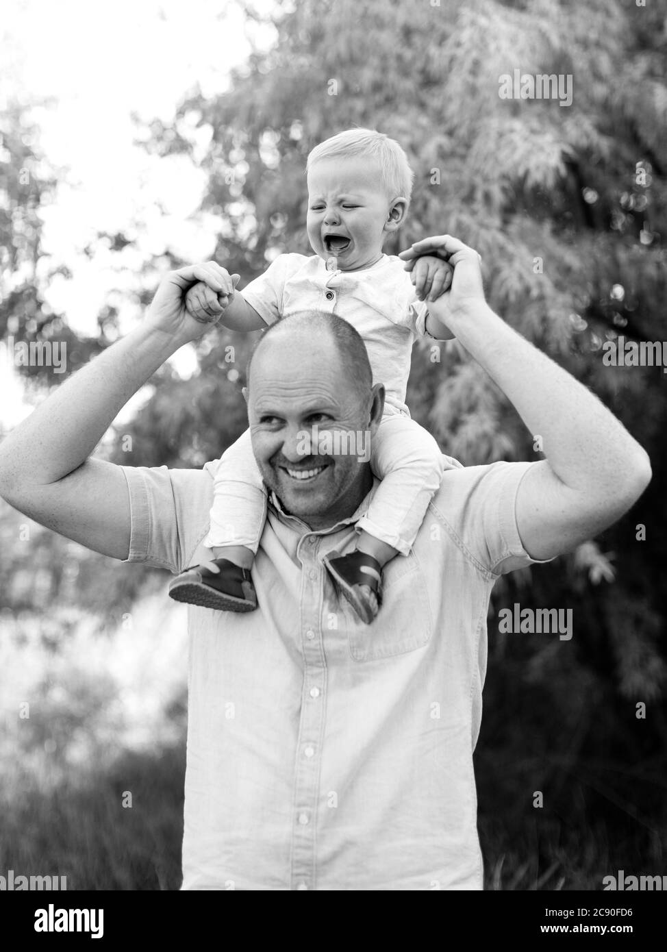 Glücklicher Vater trägt Baby Sohn auf Schultern Stockfoto