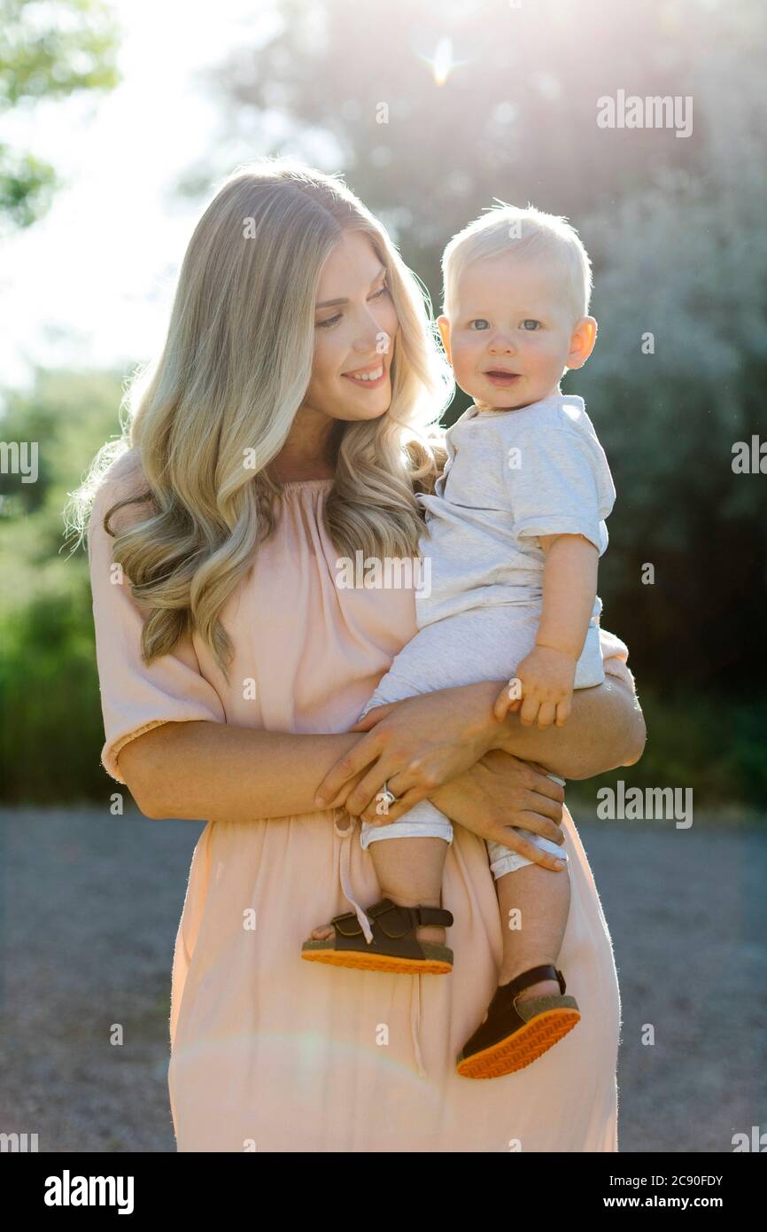 Mutter trägt lächelnd Baby Sohn Stockfoto