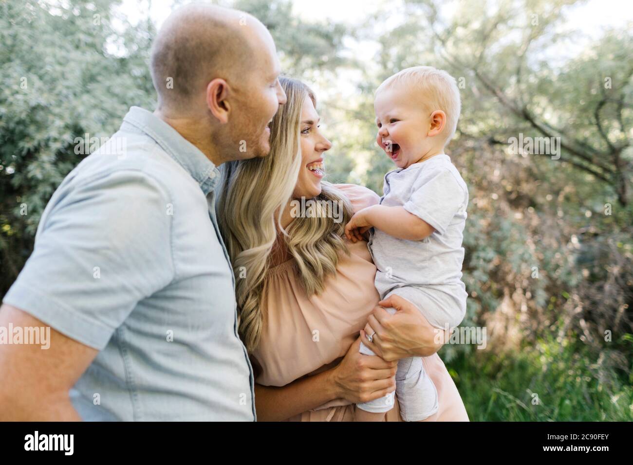 Glückliche Eltern mit Baby Sohn lachend im Garten Stockfoto