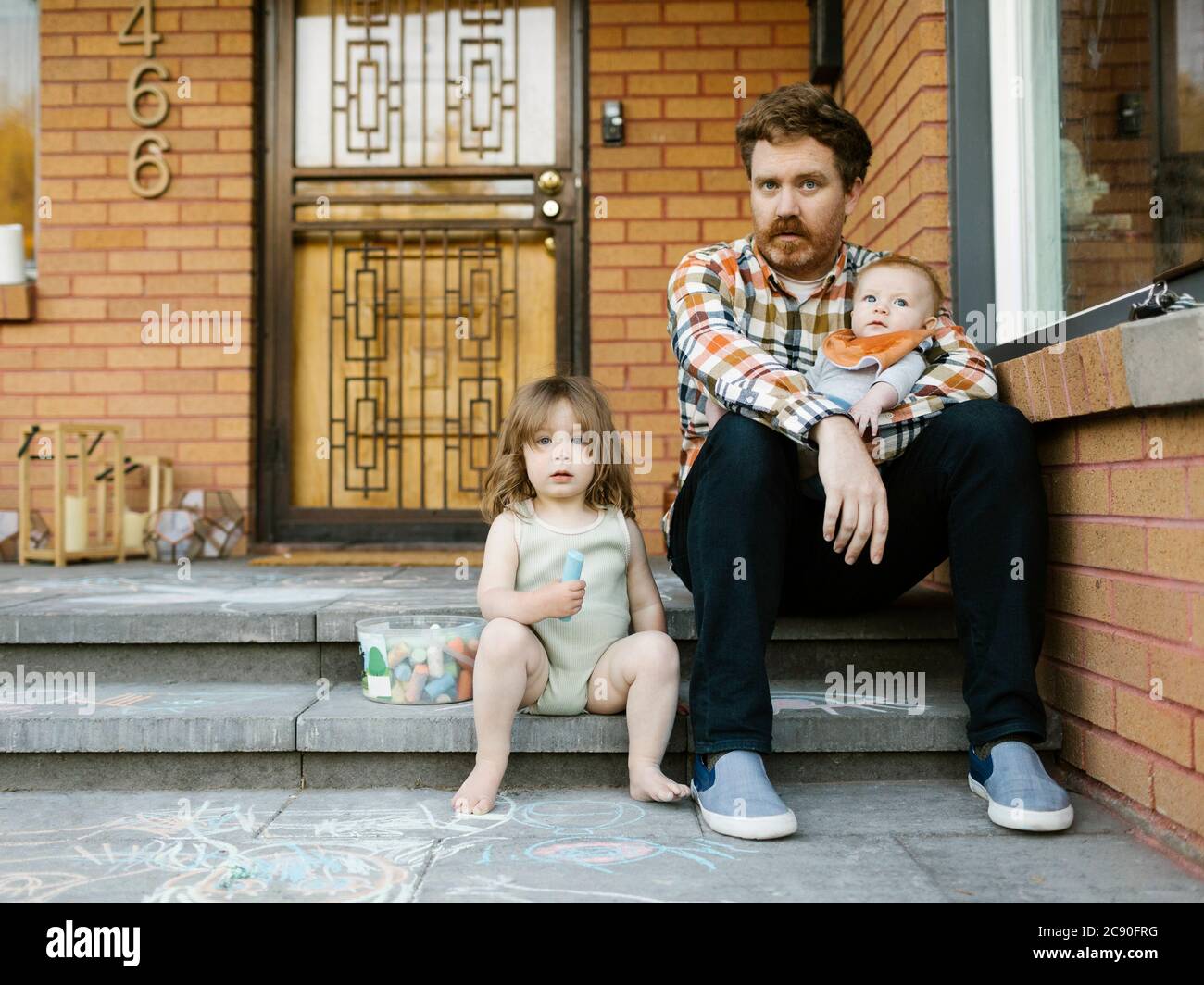 Vater sitzt auf der Veranda mit Tochter (2-3) und Sohn (6-11 Monate) Stockfoto
