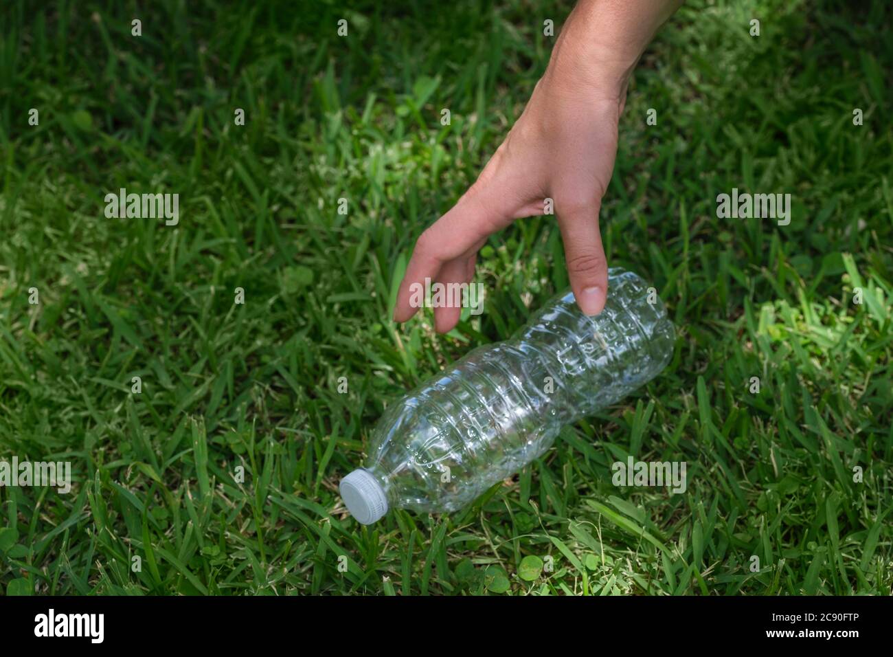 Hand der Frau nimmt Plastikflasche auf Stockfoto