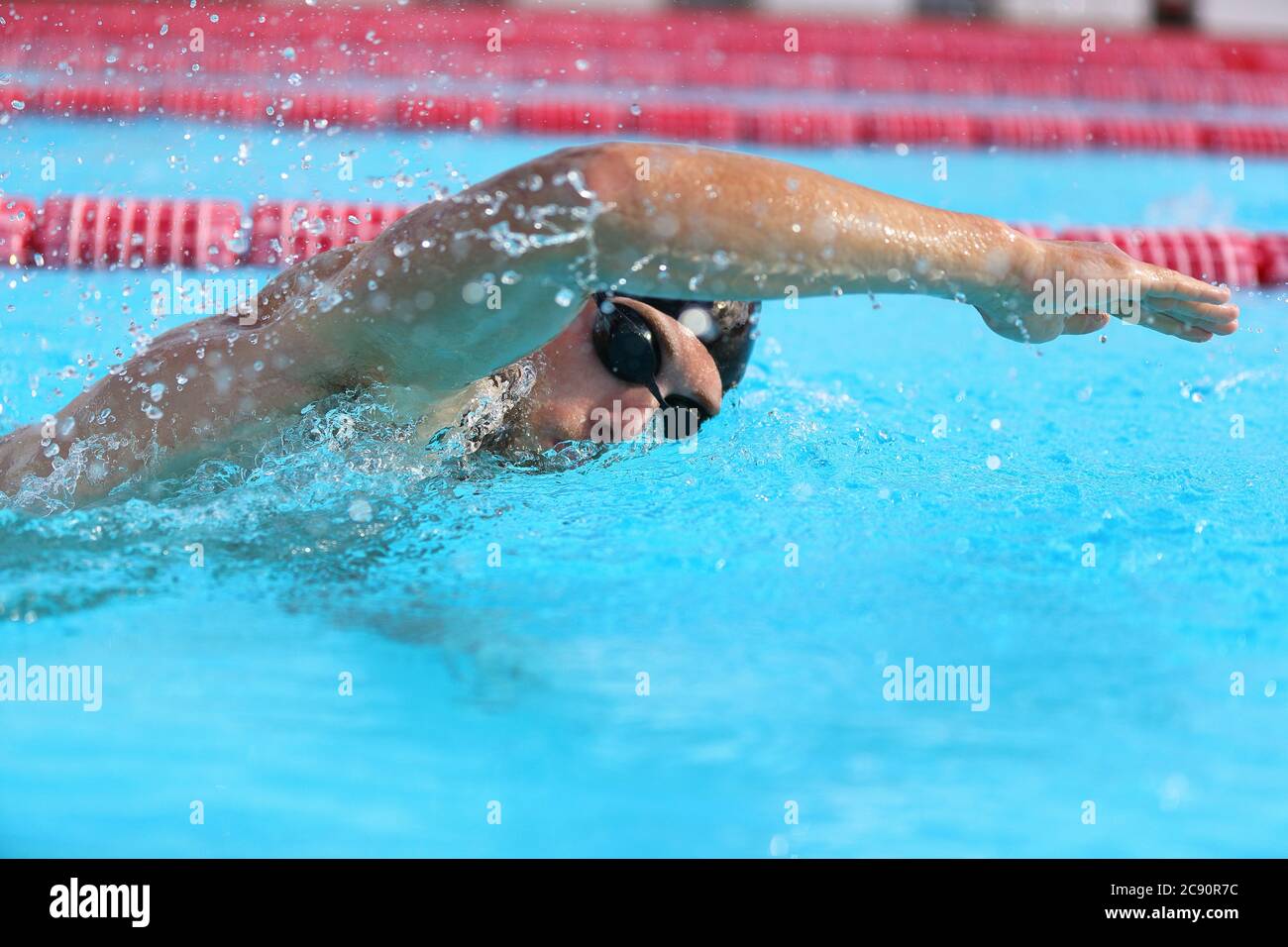 Schwimmbadsportler beim Krabbelschwimmen. Schwimmer mit Schutzbrille und Mütze Training im Stadion für die Übung. Cardio-Training Stockfoto