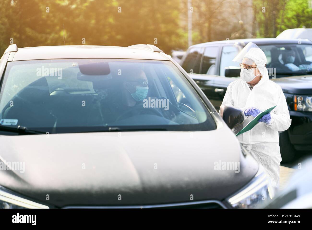 Medizinisches Personal, das einen Krankengeschichte-Bericht eines Patienten als Reaktion auf COVID-19 in Drive-Thru-Punkt aufnahm. Stockfoto