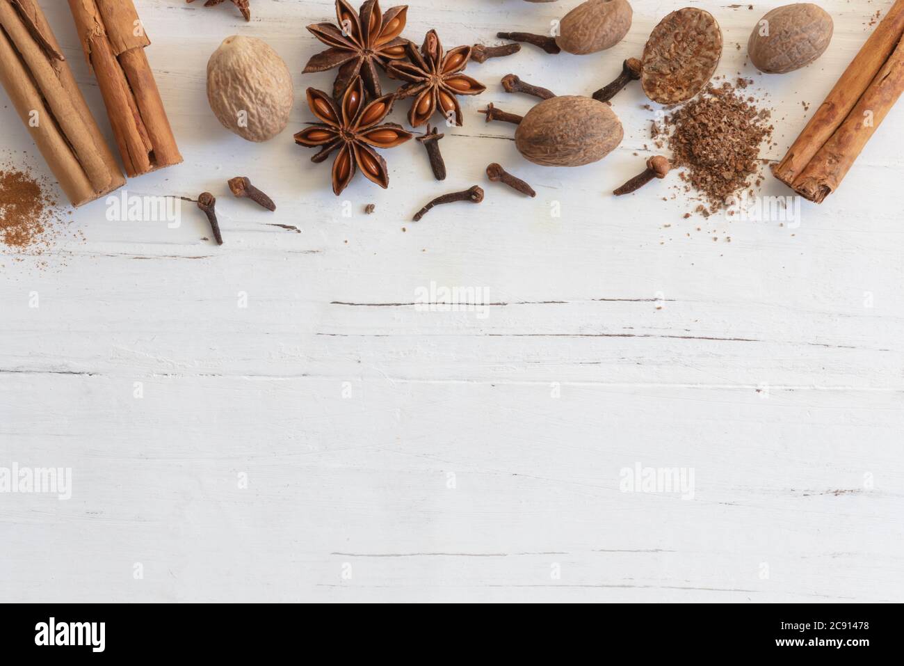 Mischung aus Gewürzen, Zimt, Muskatnuss, Sternanis und Nelken auf strukturiertem Weißholz. Flach liegend, Draufsicht, mit Kopierplatz. Weihnachten Weihnachten Gewürze. Stockfoto