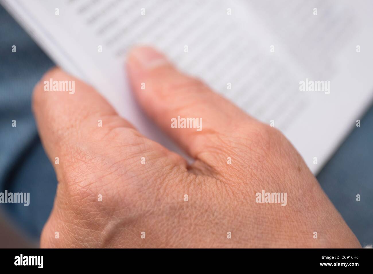 Nahaufnahme einer Hand beim Lesen eines Magazins, enge Schärfentiefe, Fokus auf die Hand Stockfoto
